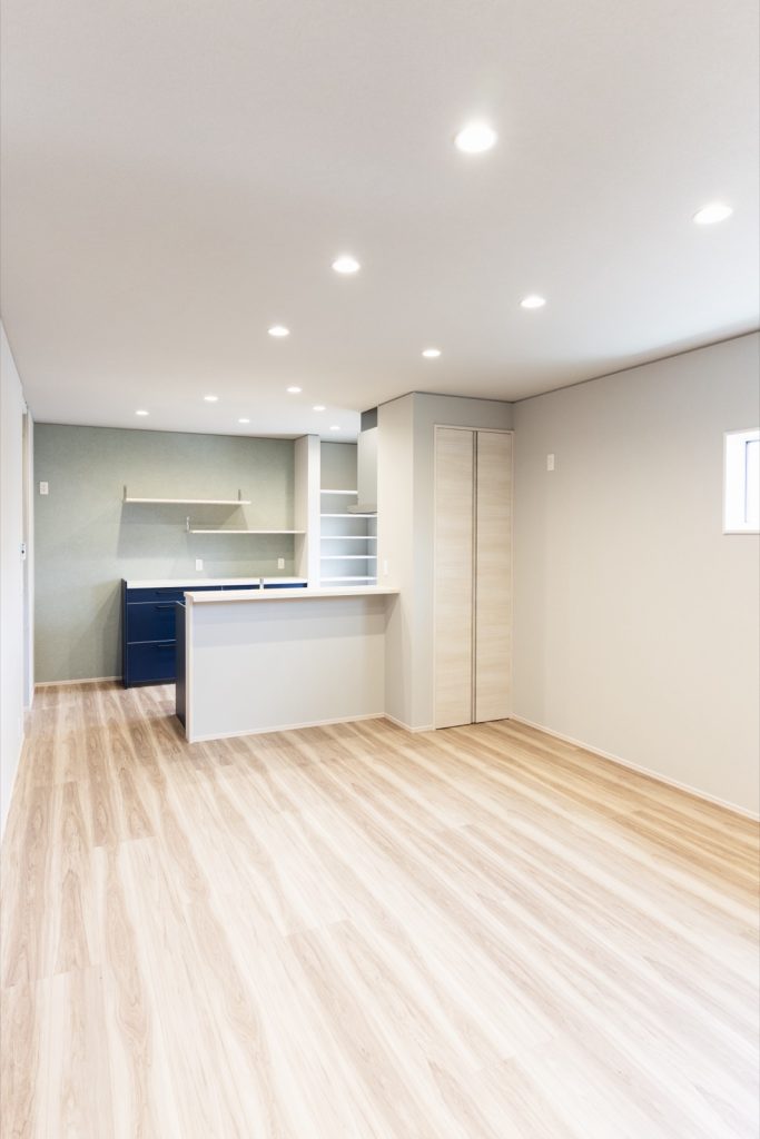 明るいメープル系の床とネイビーのキッチンでまとめた越前市の注文住宅のLDK全景